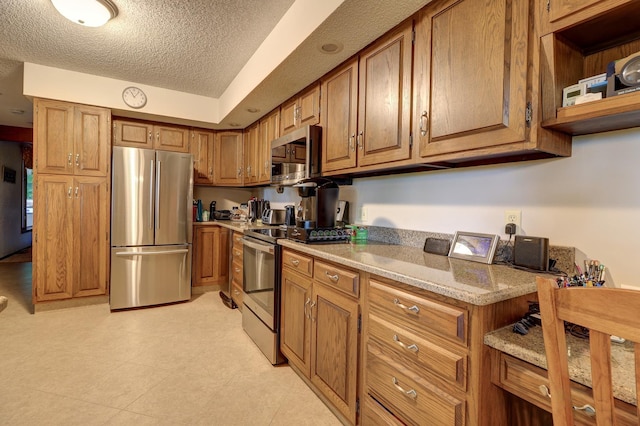 kitchen featuring brown cabinets, stainless steel appliances, and a textured ceiling