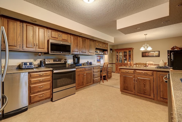 kitchen featuring light countertops, appliances with stainless steel finishes, decorative light fixtures, and brown cabinets