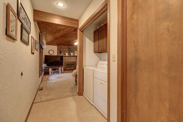 washroom with a textured ceiling, a textured wall, light colored carpet, separate washer and dryer, and cabinet space