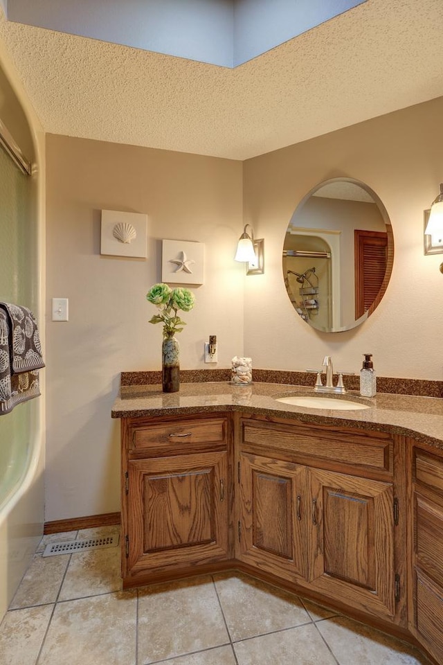 full bath with a textured ceiling, vanity, baseboards, visible vents, and tile patterned floors