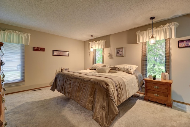 carpeted bedroom featuring a textured ceiling, multiple windows, visible vents, and baseboards