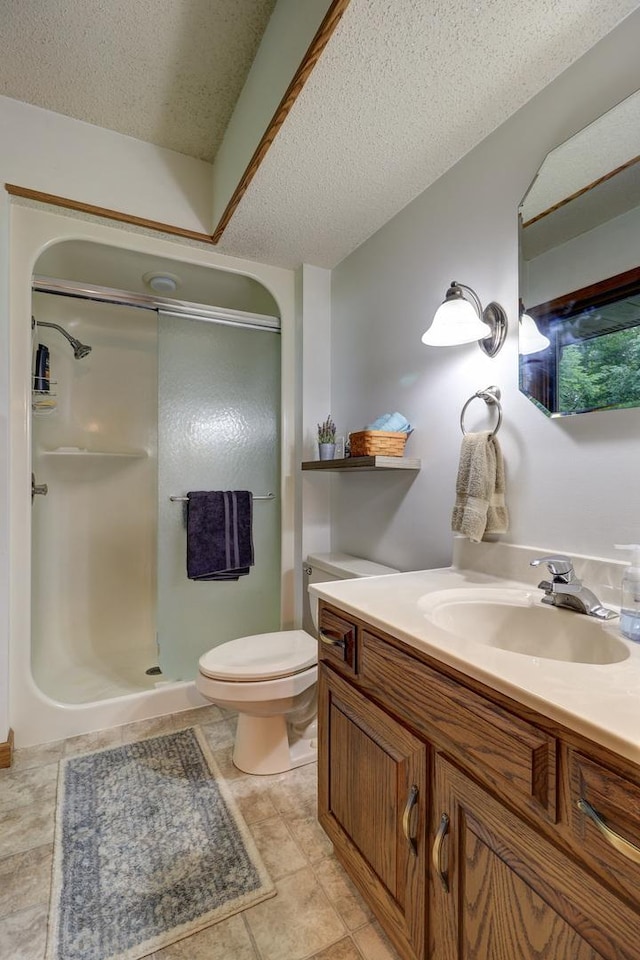 bathroom with toilet, a shower stall, a textured ceiling, and vanity