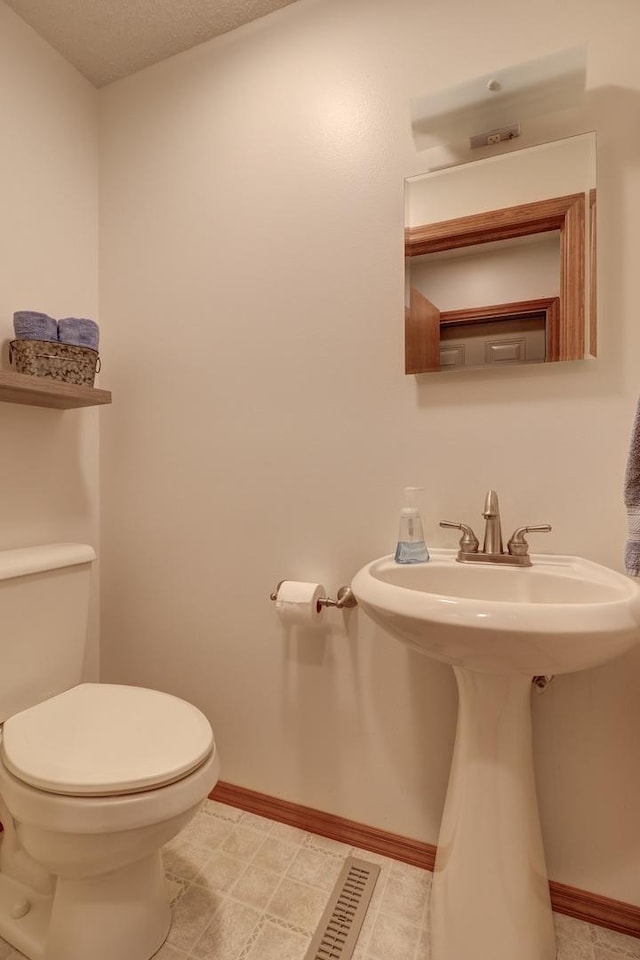 bathroom featuring a sink, toilet, and baseboards