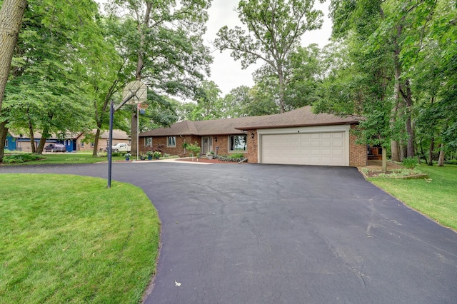 ranch-style house featuring driveway, a front lawn, an attached garage, and brick siding