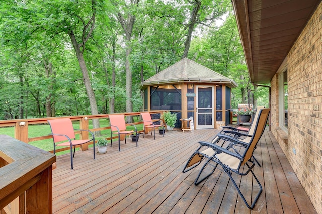 deck featuring a sunroom and a wooded view