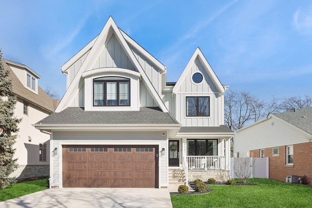 view of front of home with driveway, an attached garage, a porch, board and batten siding, and a front yard