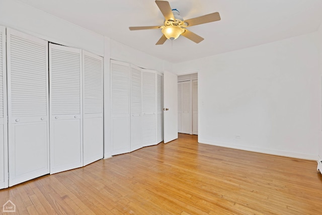 unfurnished bedroom featuring light wood-style flooring, baseboards, ceiling fan, and multiple closets