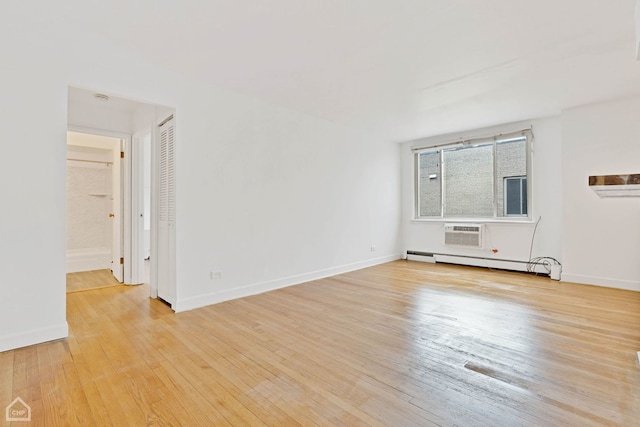 empty room featuring a wall unit AC, light wood finished floors, baseboards, and baseboard heating