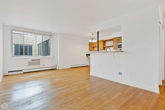 unfurnished living room with a chandelier, light wood finished floors, and baseboard heating