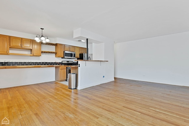 kitchen with decorative light fixtures, stainless steel appliances, light wood-style floors, a chandelier, and open shelves