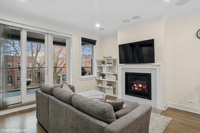 living room with a fireplace, recessed lighting, ornamental molding, wood finished floors, and baseboards