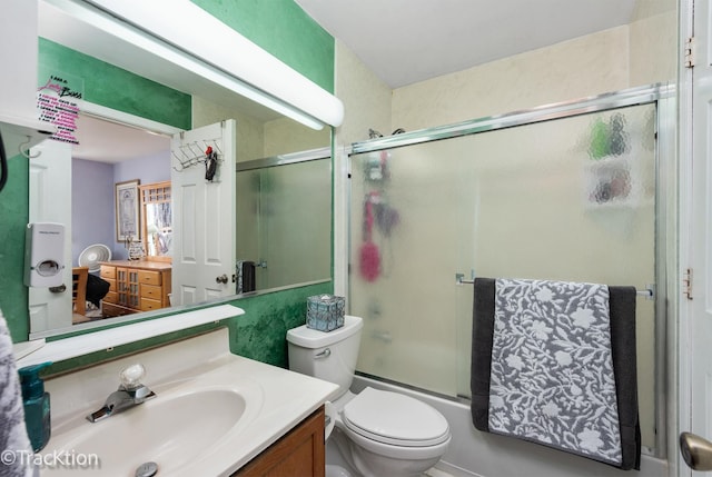 bathroom featuring toilet, shower / bath combination with glass door, and vanity