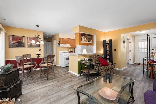 living room featuring baseboards, wood finished floors, and an inviting chandelier