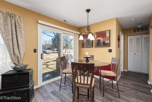 dining area featuring a chandelier, dark wood-type flooring, visible vents, and baseboards