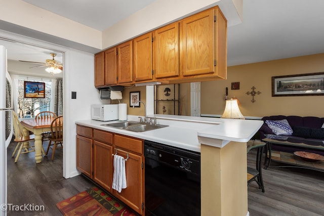 kitchen featuring white microwave, a peninsula, dark wood-type flooring, a sink, and dishwasher