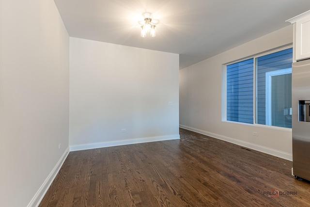 spare room featuring baseboards and dark wood finished floors