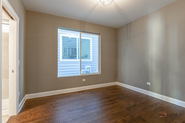 spare room featuring dark wood finished floors and baseboards