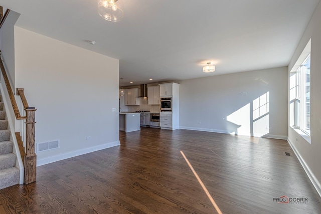 unfurnished living room featuring dark wood-style flooring, recessed lighting, visible vents, stairway, and baseboards