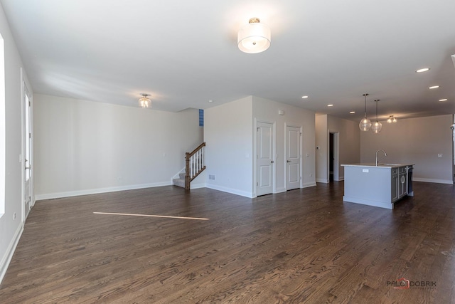 unfurnished living room with stairway, dark wood finished floors, a sink, and recessed lighting