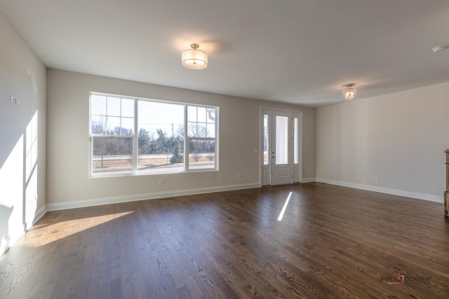 spare room with dark wood-style flooring and baseboards