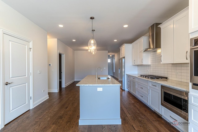 kitchen featuring appliances with stainless steel finishes, a sink, wall chimney exhaust hood, and dark wood-style floors