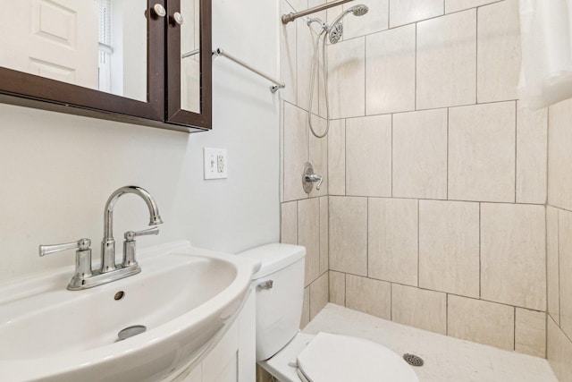 full bathroom featuring toilet, a sink, and tiled shower