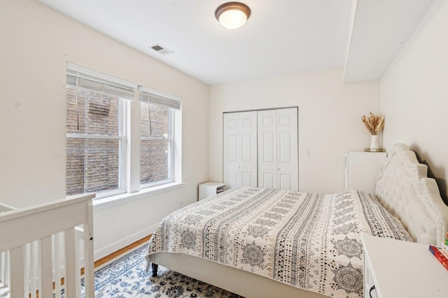 bedroom featuring a closet, visible vents, baseboards, and wood finished floors