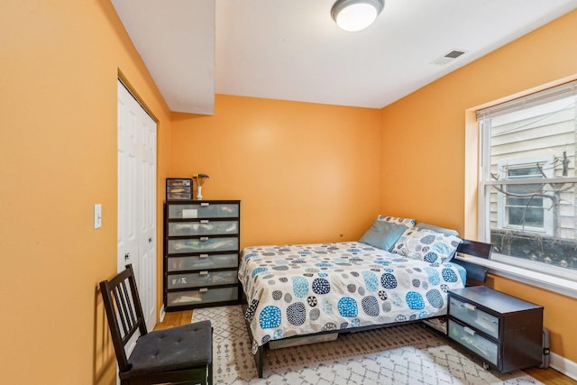 bedroom featuring a closet, visible vents, baseboards, and wood finished floors