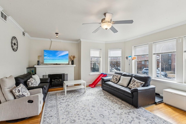 living room with crown molding, a fireplace, and wood finished floors