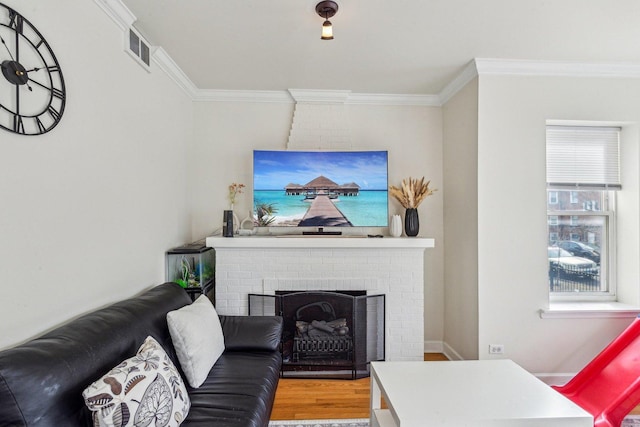 living room featuring a fireplace, wood finished floors, visible vents, and crown molding