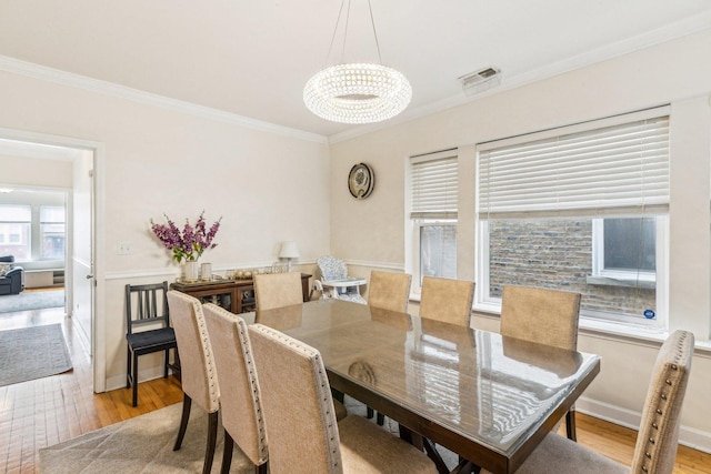 dining room featuring a chandelier, hardwood / wood-style floors, visible vents, and crown molding