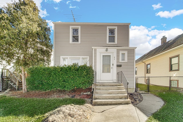 view of front of property featuring entry steps, a front yard, fence, and a gate