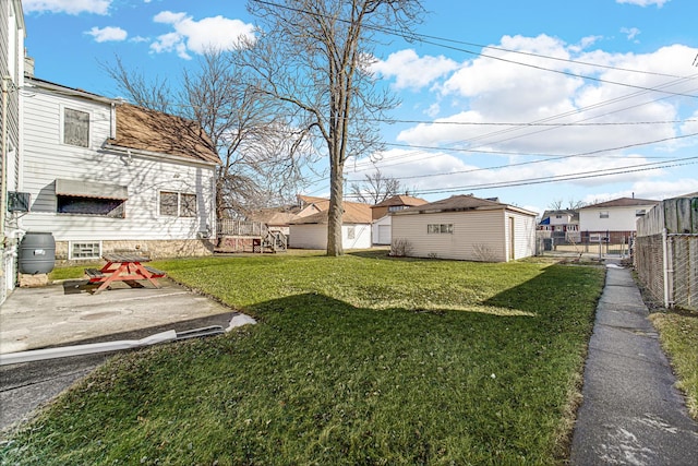 view of yard featuring an outdoor structure, fence, and a residential view