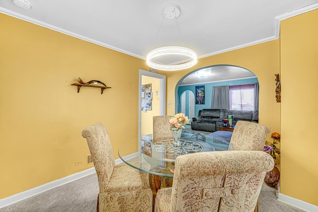 carpeted dining room featuring arched walkways, ornamental molding, and baseboards