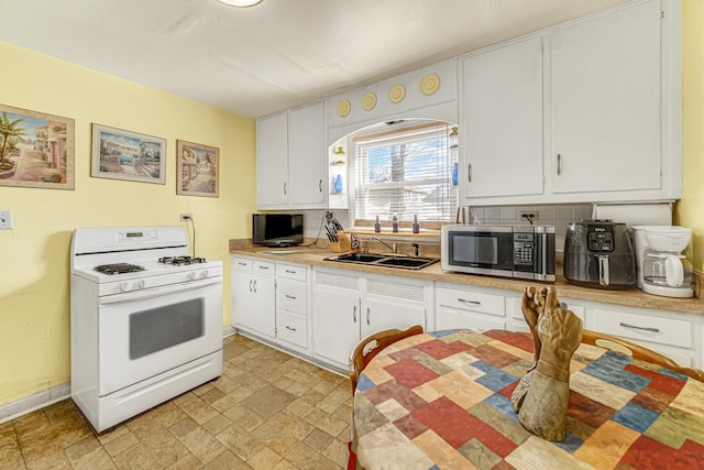 kitchen with light countertops, stainless steel microwave, white range with gas cooktop, and white cabinetry