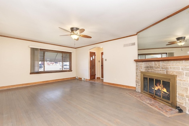 unfurnished living room featuring arched walkways, visible vents, a stone fireplace, wood finished floors, and baseboards