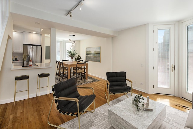 living room featuring track lighting, visible vents, baseboards, and wood finished floors