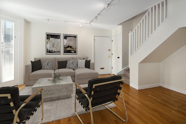 living room with a healthy amount of sunlight, stairway, baseboards, and wood finished floors