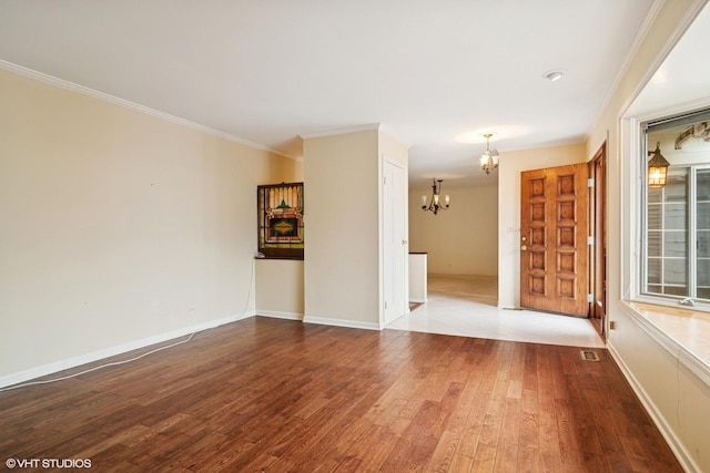 unfurnished room featuring wood finished floors, visible vents, crown molding, and an inviting chandelier