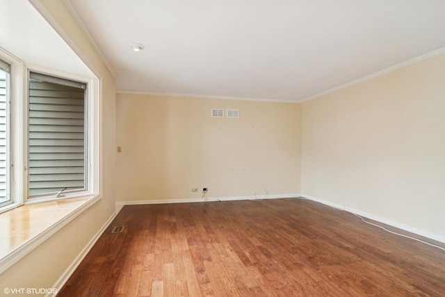 spare room featuring ornamental molding, wood-type flooring, and baseboards