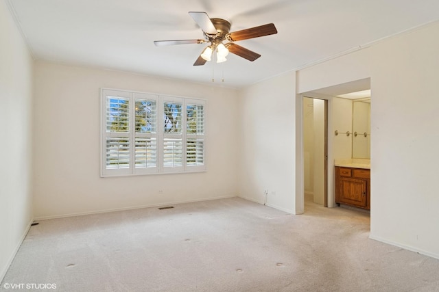 unfurnished bedroom featuring light carpet, baseboards, ornamental molding, and ensuite bathroom