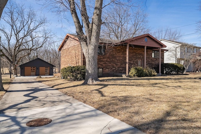 view of home's exterior with an outbuilding, concrete driveway, and brick siding