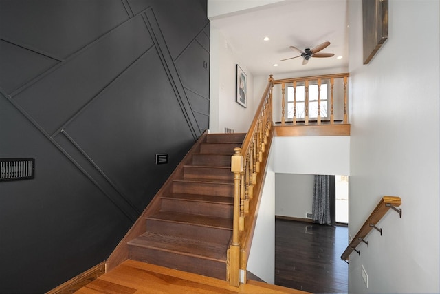 staircase featuring ceiling fan, baseboards, wood finished floors, and recessed lighting