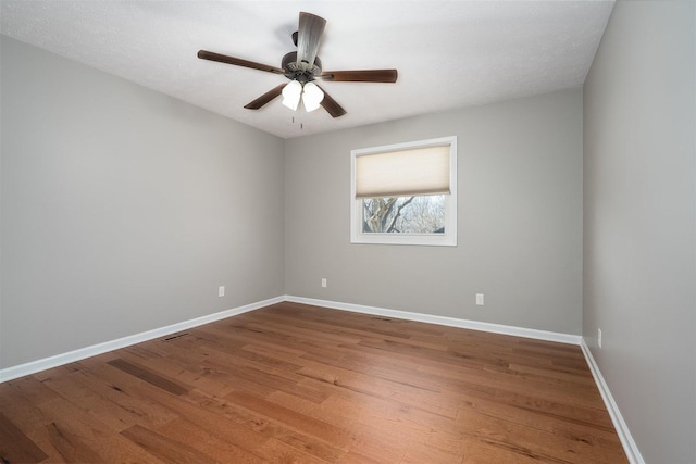 spare room with ceiling fan, wood finished floors, visible vents, and baseboards