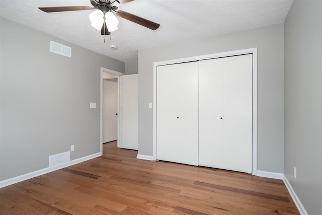 unfurnished bedroom featuring baseboards, visible vents, a textured ceiling, light wood-style floors, and a closet