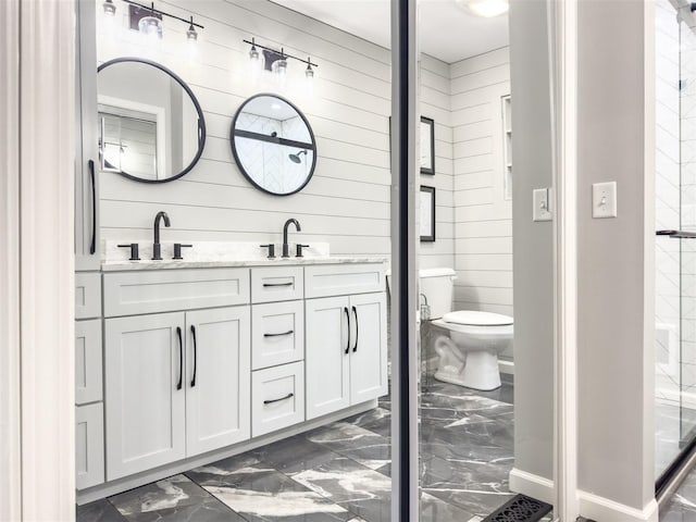 bathroom with marble finish floor, double vanity, a sink, and toilet