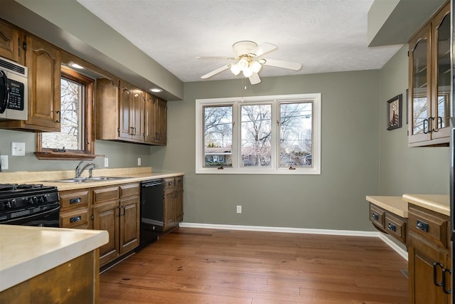 kitchen featuring black appliances, dark wood-style flooring, a sink, and light countertops