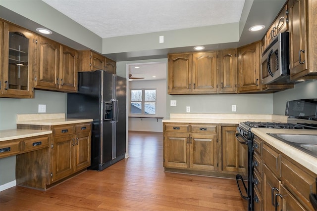 kitchen featuring light wood-type flooring, light countertops, and black appliances