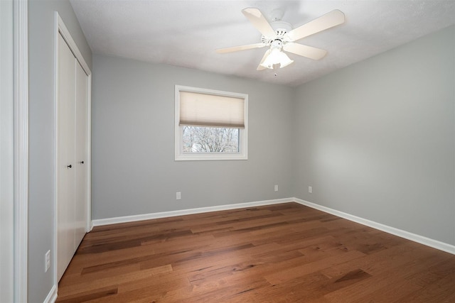 unfurnished bedroom with a ceiling fan, a closet, baseboards, and wood finished floors