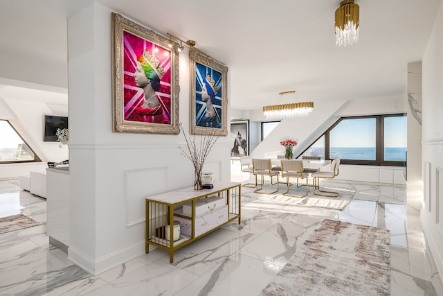 corridor with a chandelier, marble finish floor, and baseboards